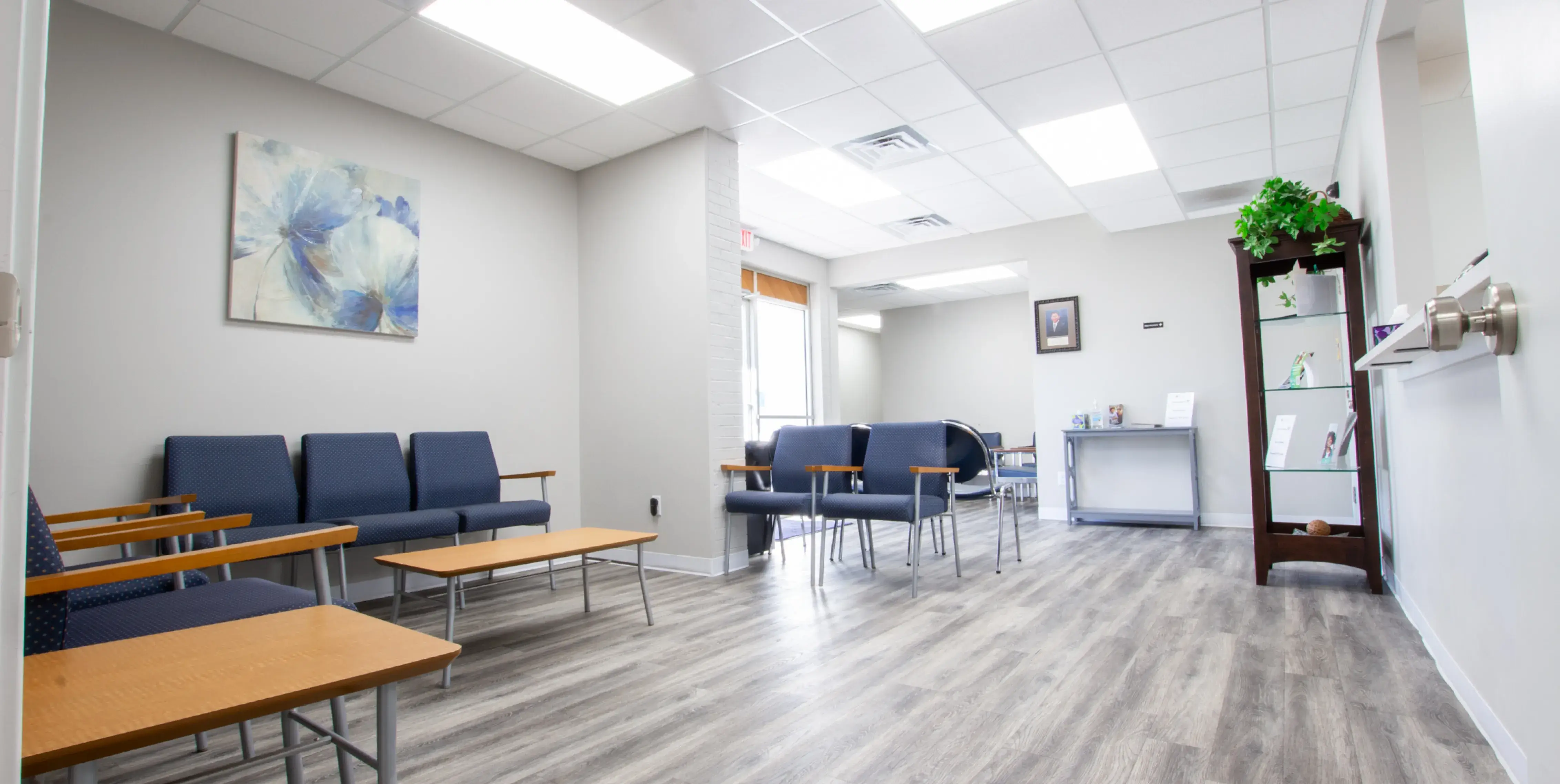 a waiting room with blue chairs and wooden tables